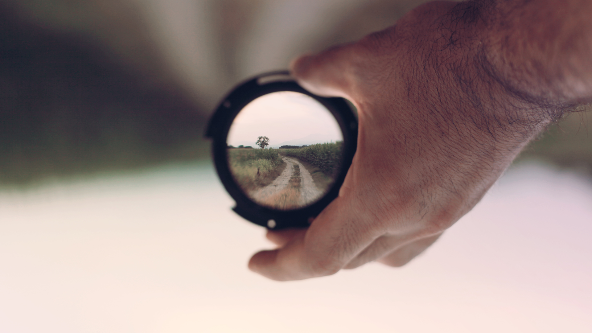 Hand holding focusing lens on horizon